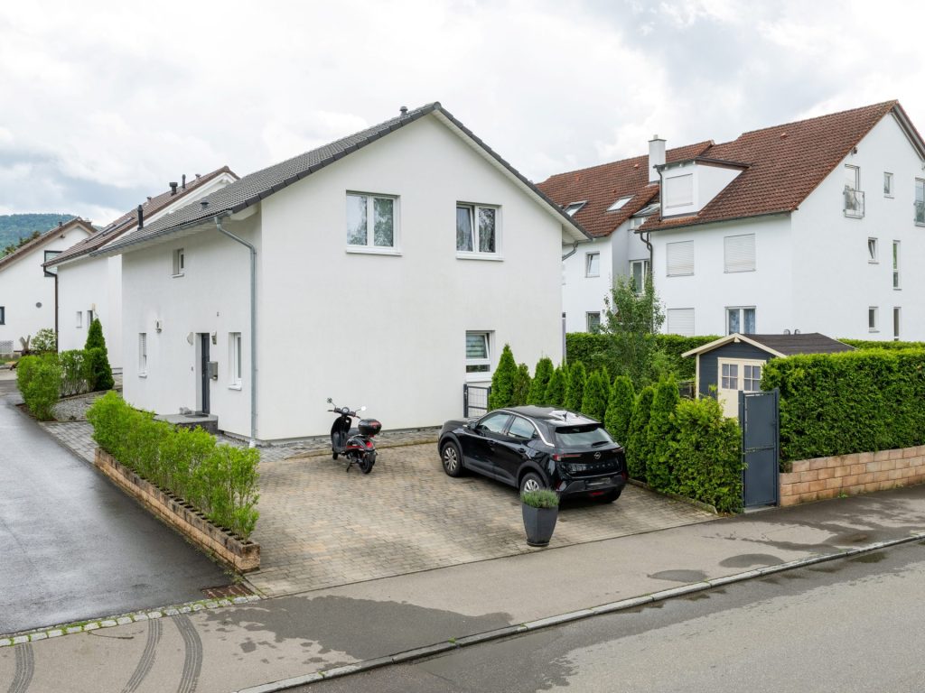 Ein Wohnhaus mit einem geparkten Auto im Vordergrund.