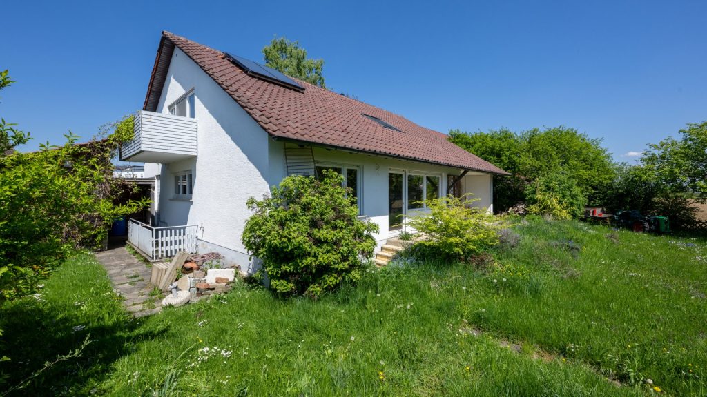 Ein Haus mit einem gepflegten Garten und einer grünen Rasenfläche.