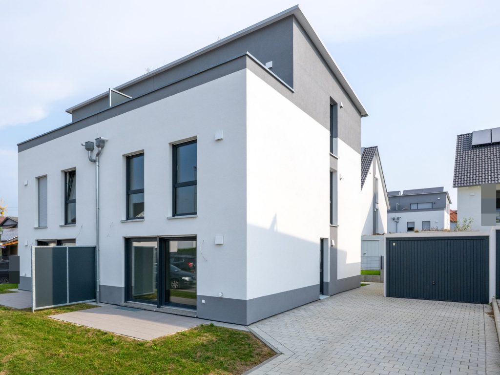 Modernes Haus mit Garage und Solarpanelen auf dem Dach, umweltfreundlich und energieeffizient gestaltet.
